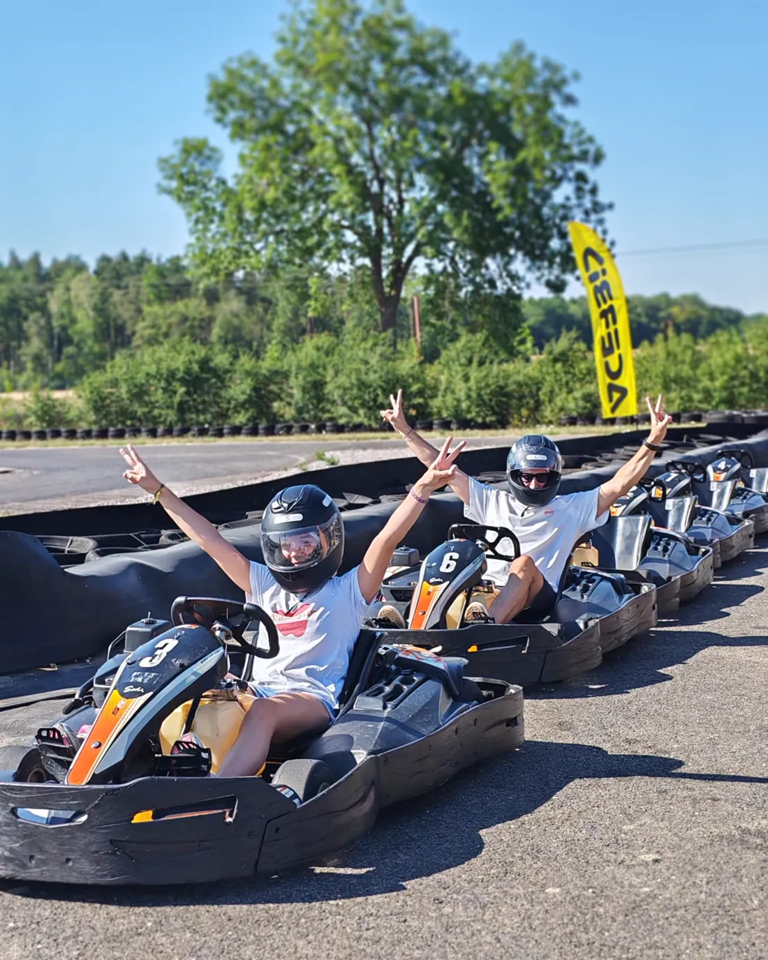Pilotes en kart, bras levés, sur la ligne de départ