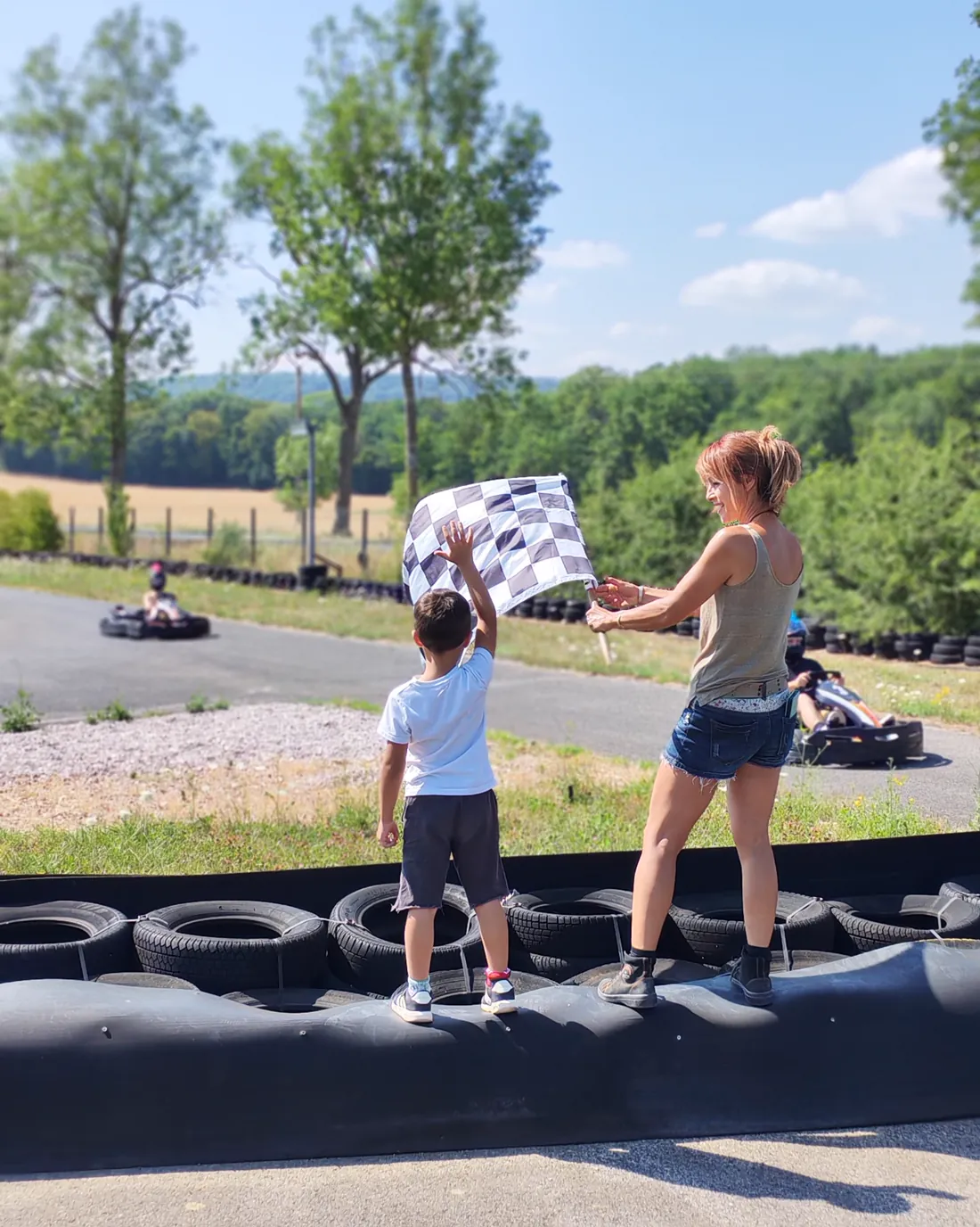 Un enfant et un adulte agitent le drapeau à damier au bord de la piste