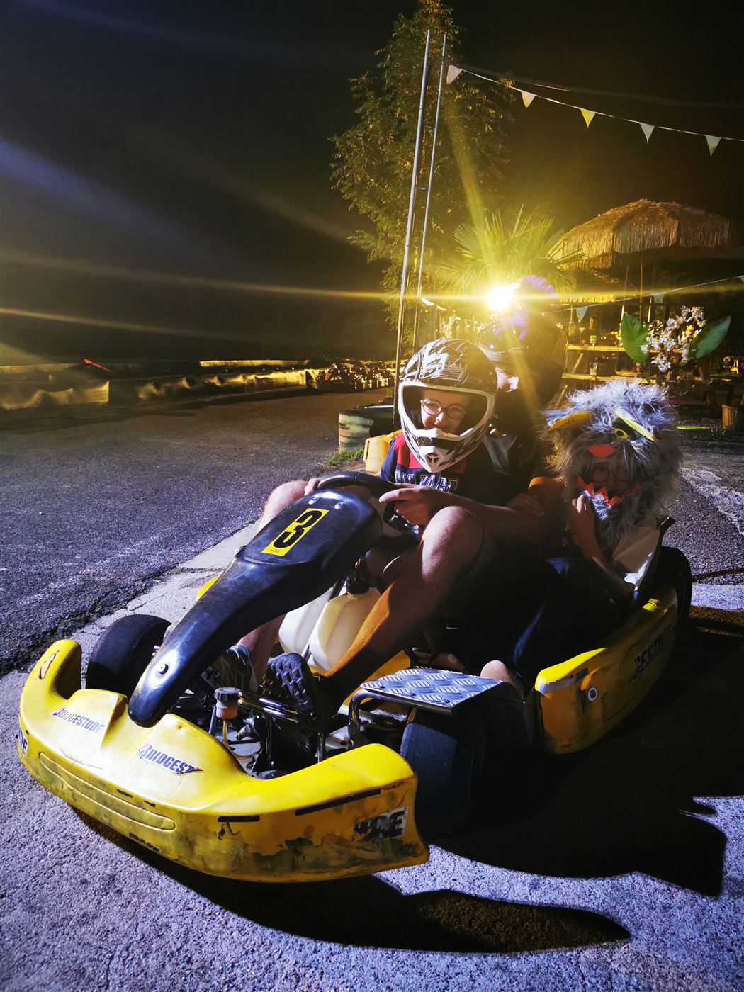 Kart jaune de nuit, pilote casqué sous les projecteurs