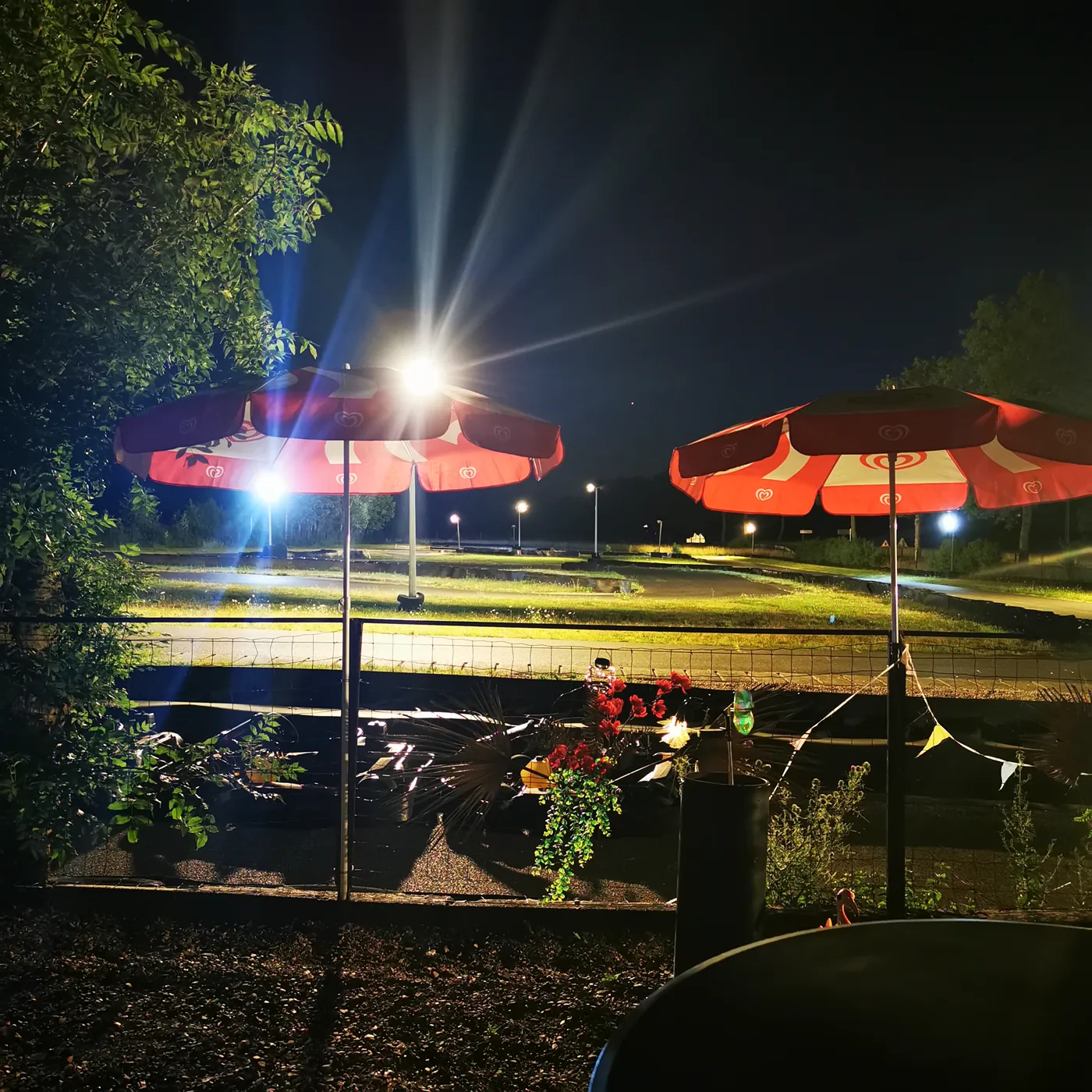 La piste de Kart'Hell éclairée de nuit, parasols rouges au bord