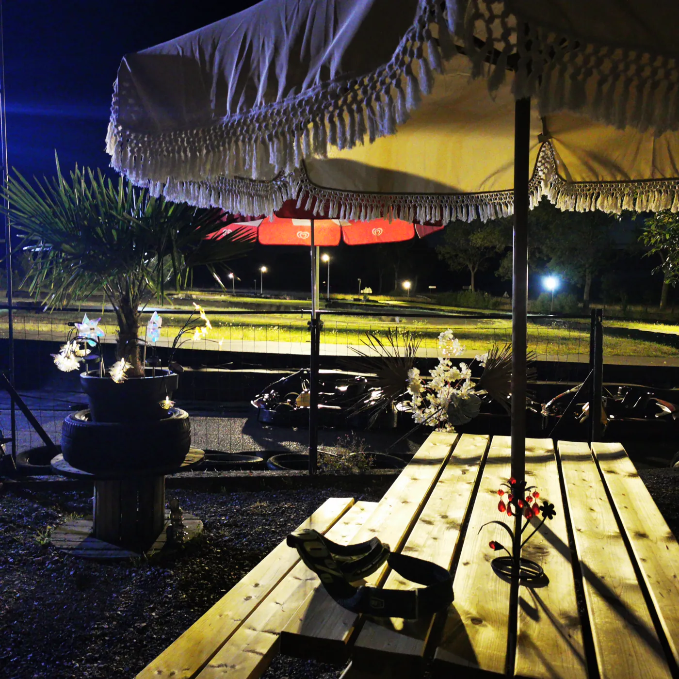 La terrasse de nuit, sous un parasol, face à la piste éclairée